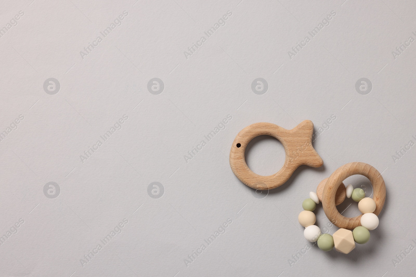 Photo of Baby accessories. Rattle and teether on grey background, top view. Space for text