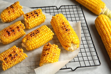 Cooling rack with grilled corn cobs on light background