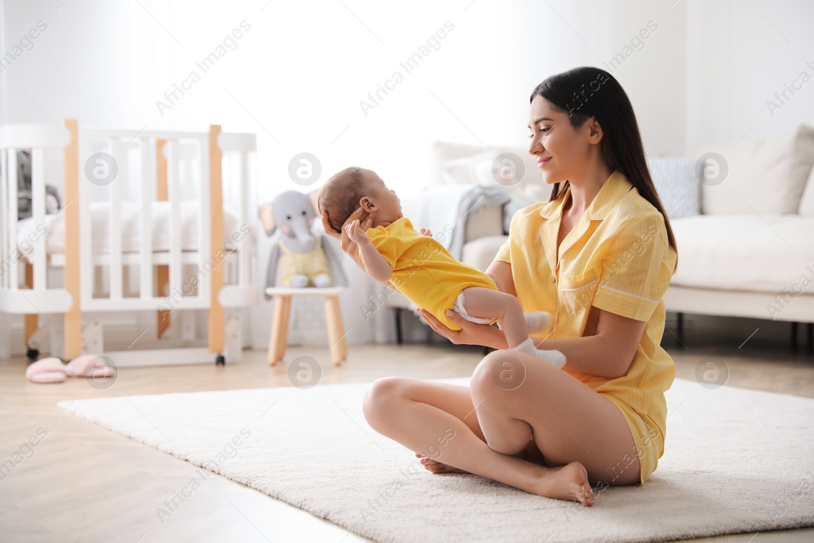 Photo of Young woman with her cute baby at home, space for text