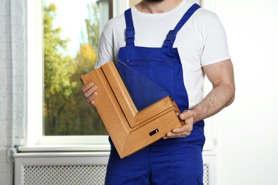 Installation worker with sample of modern window profile indoors