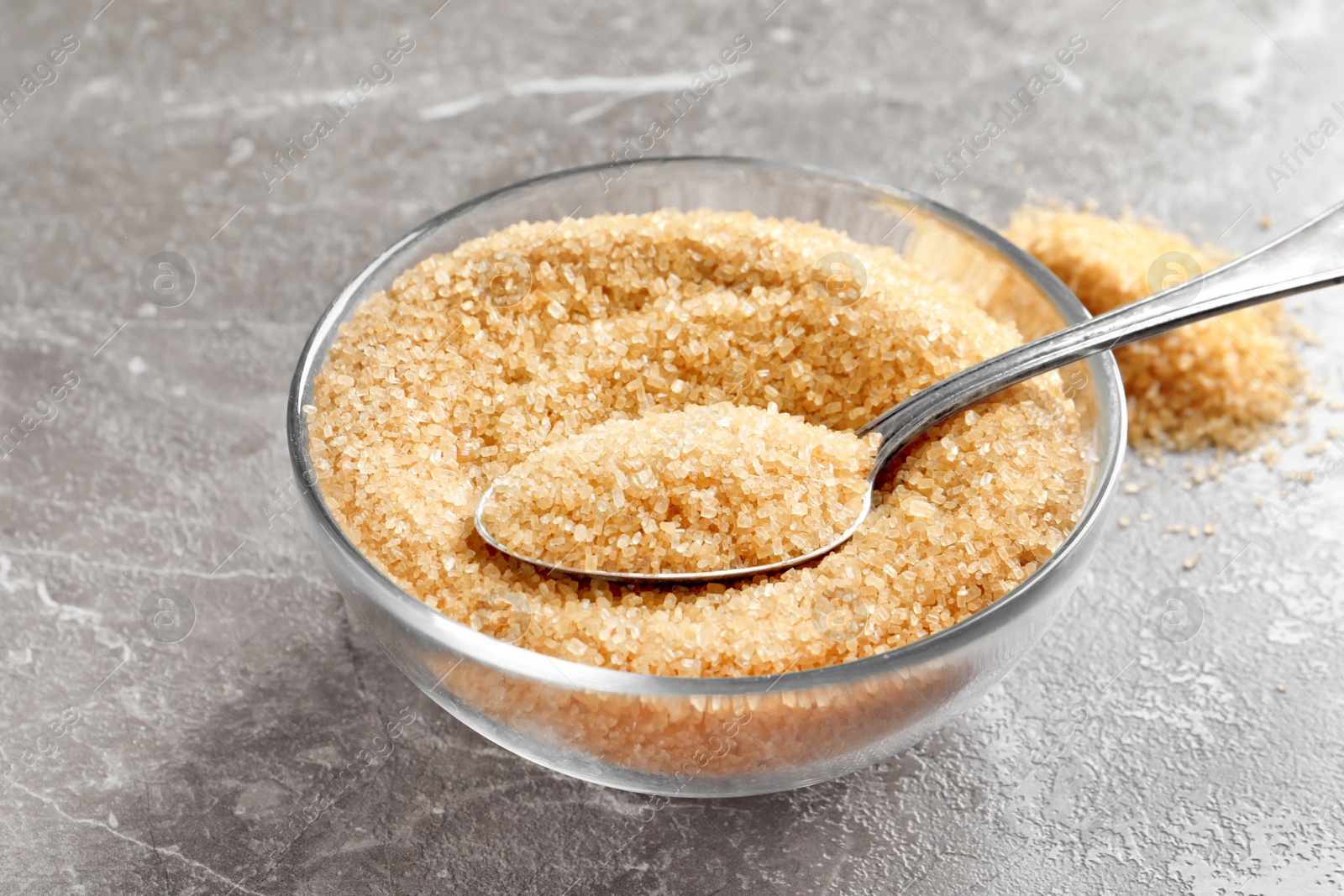 Photo of Spoon with brown sugar in bowl on table