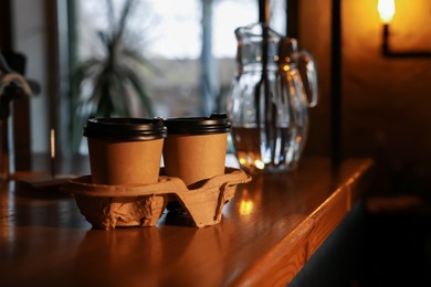Photo of Paper coffee cups on wooden table in cafe. Space for text