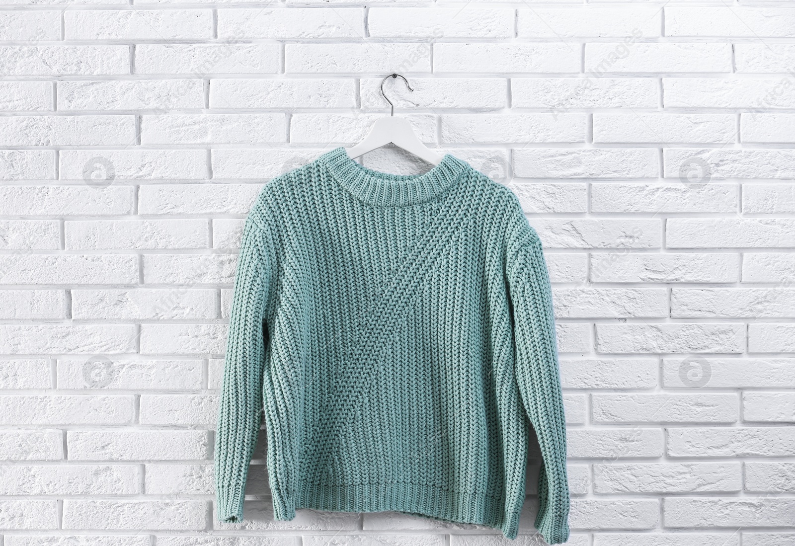 Photo of Hanger with stylish sweater on brick wall