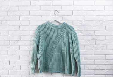 Photo of Hanger with stylish sweater on brick wall