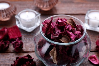Photo of Aromatic potpourri of dried flowers in glass jar on wooden table, closeup