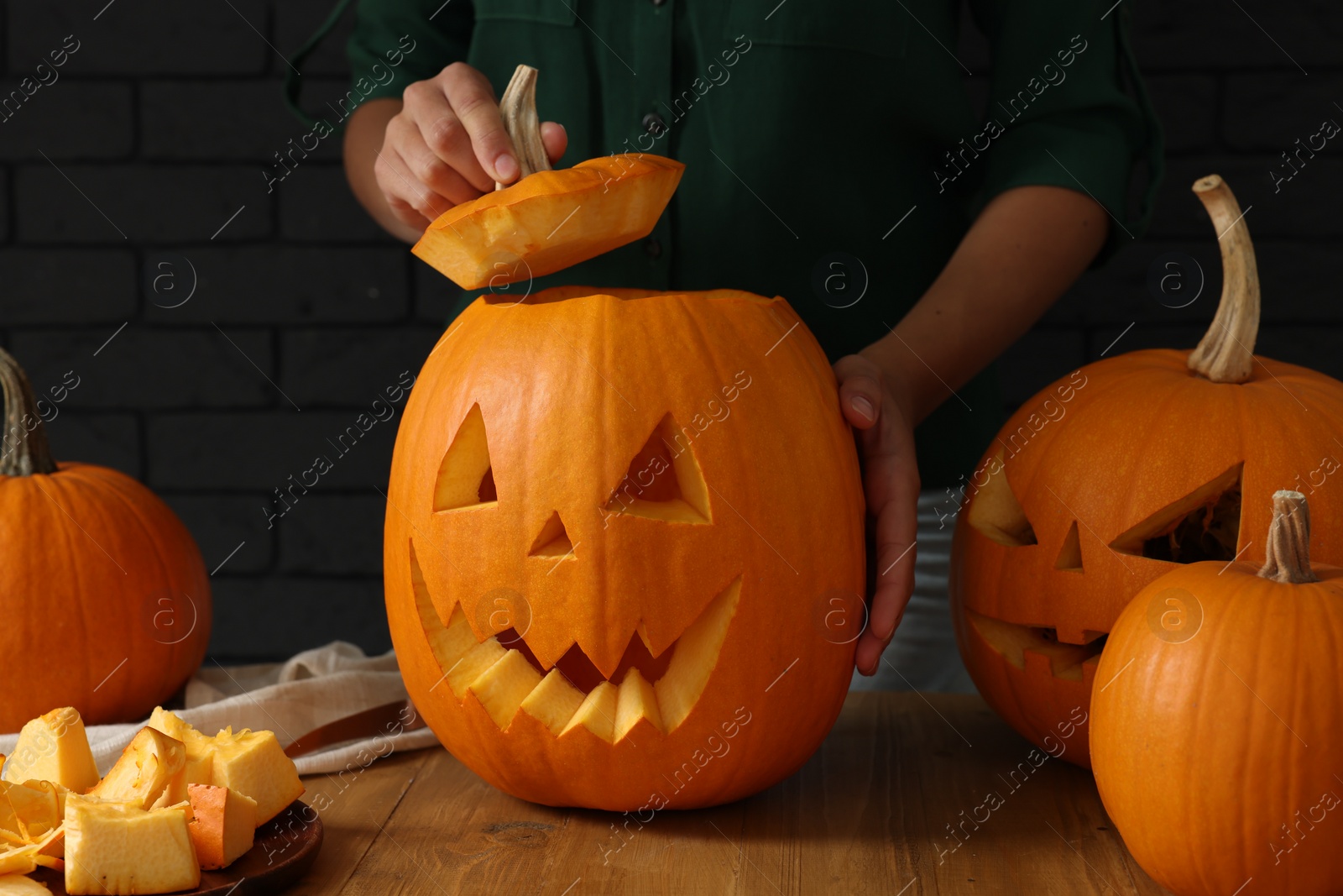 Photo of Woman with carved pumpkins at wooden table, closeup. Halloween celebration