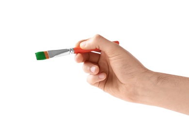 Photo of Young man holding brush with color paint on white background, closeup