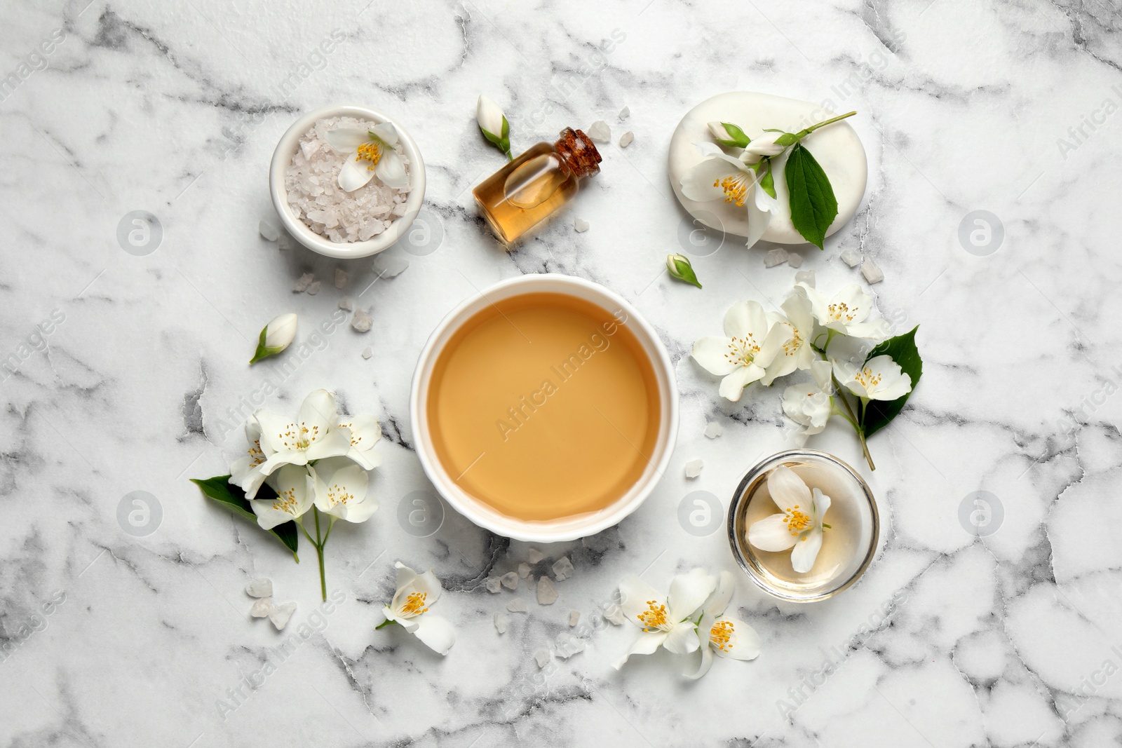 Photo of Flat lay composition with jasmine essential oil and fresh flowers on white marble table