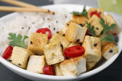 Bowl with fried tofu, rice, chili pepper and parsley on table, closeup