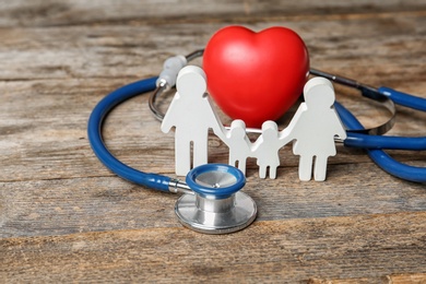 Family figure with stethoscope and heart on wooden background. Life insurance concept