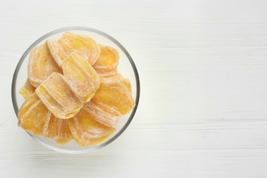 Photo of Delicious dried jackfruit slices in glass bowl on white wooden table, top view. Space for text