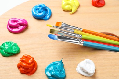 Photo of Palette with paints and brushes on white background, closeup. Artist equipment