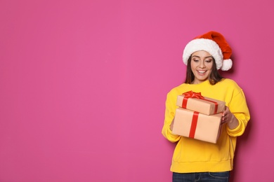 Young woman with Christmas gifts on color background