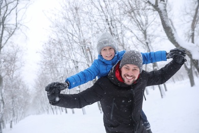 Photo of Father with his child having fun outside on winter day. Christmas vacation