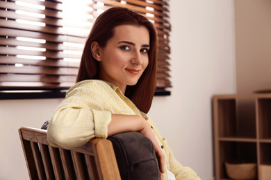 Beautiful young woman near window at home