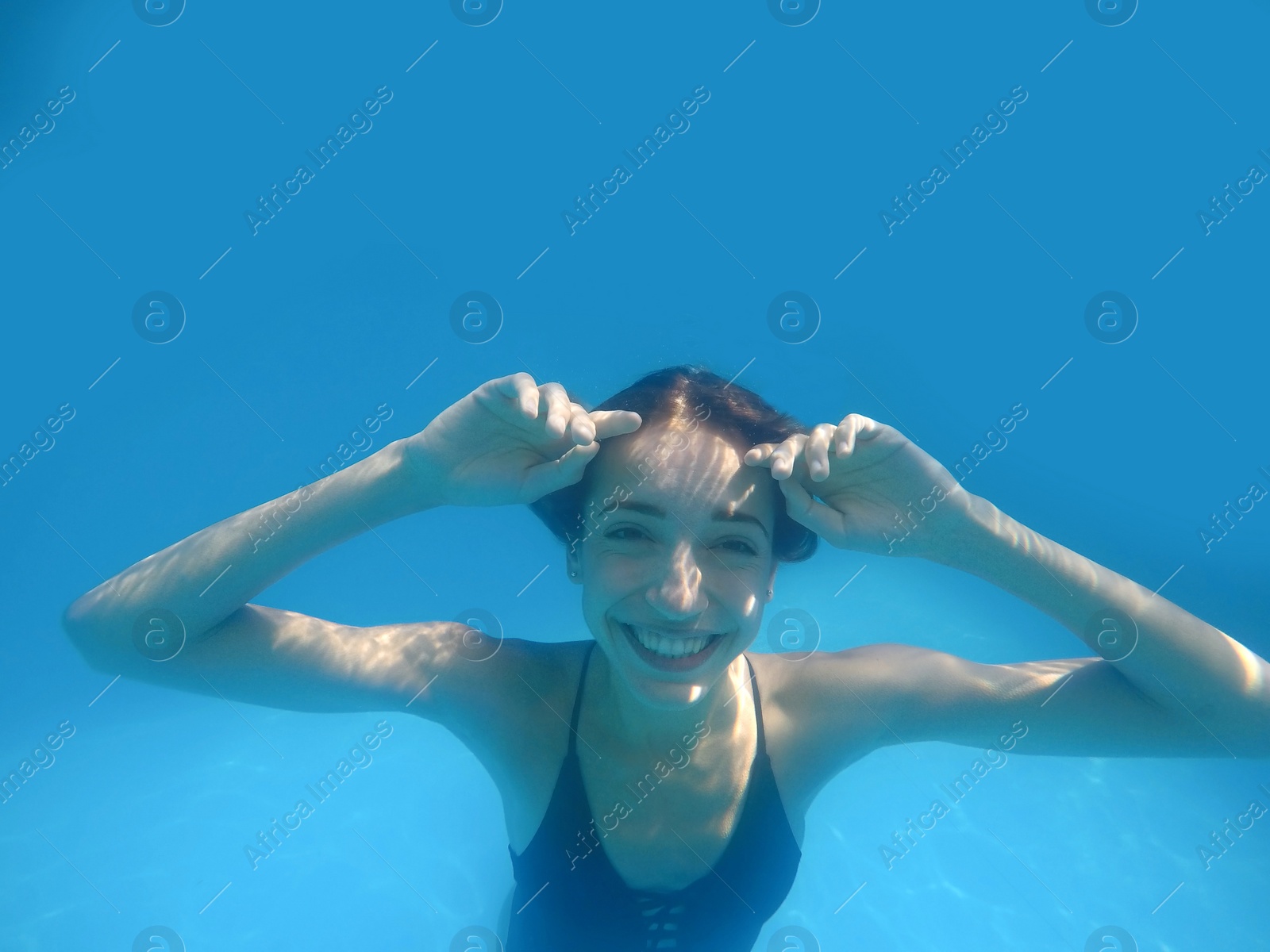 Photo of Beautiful young woman swimming in pool, underwater view