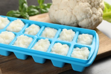 Cauliflower puree in ice cube tray on grey table, closeup. Ready for freezing