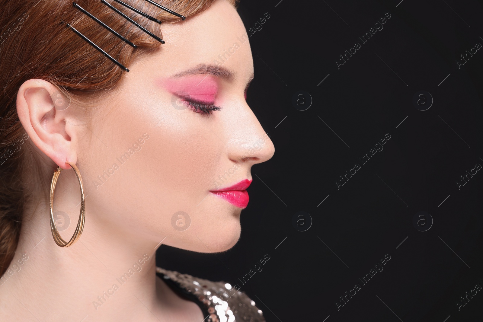 Photo of Portrait of beautiful young woman with makeup posing on black background, closeup. Space for text