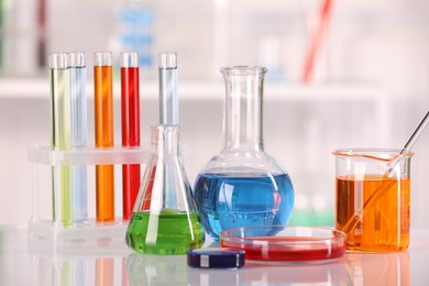 Photo of Laboratory analysis. Different glassware with liquids on white table against blurred background