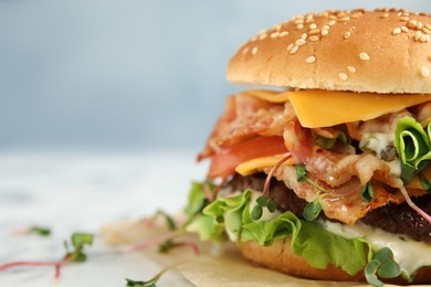 Photo of Tasty burger with bacon on table, closeup. Space for text