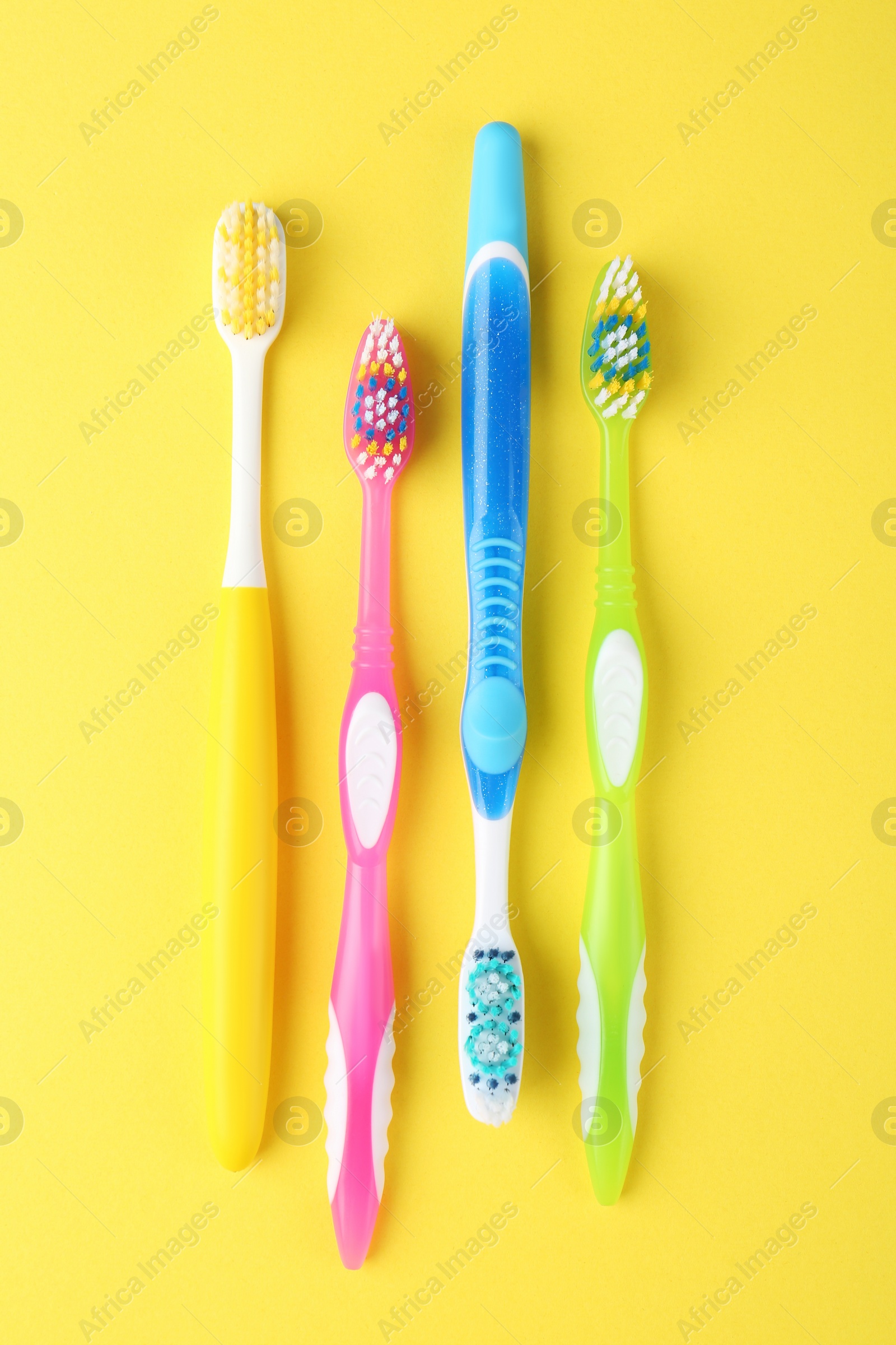 Photo of Different toothbrushes on yellow background, flat lay