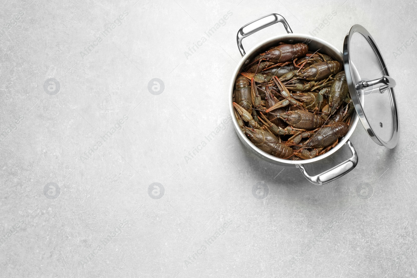 Photo of Fresh raw crayfishes in pot on grey table, top view. Space for text