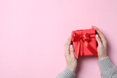 Christmas present. Woman holding gift box on pink background, top view. Space for text