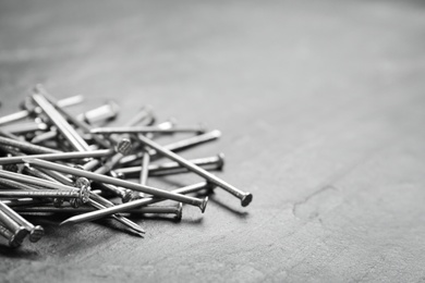 Photo of Many metal nails on grey background. Space for text