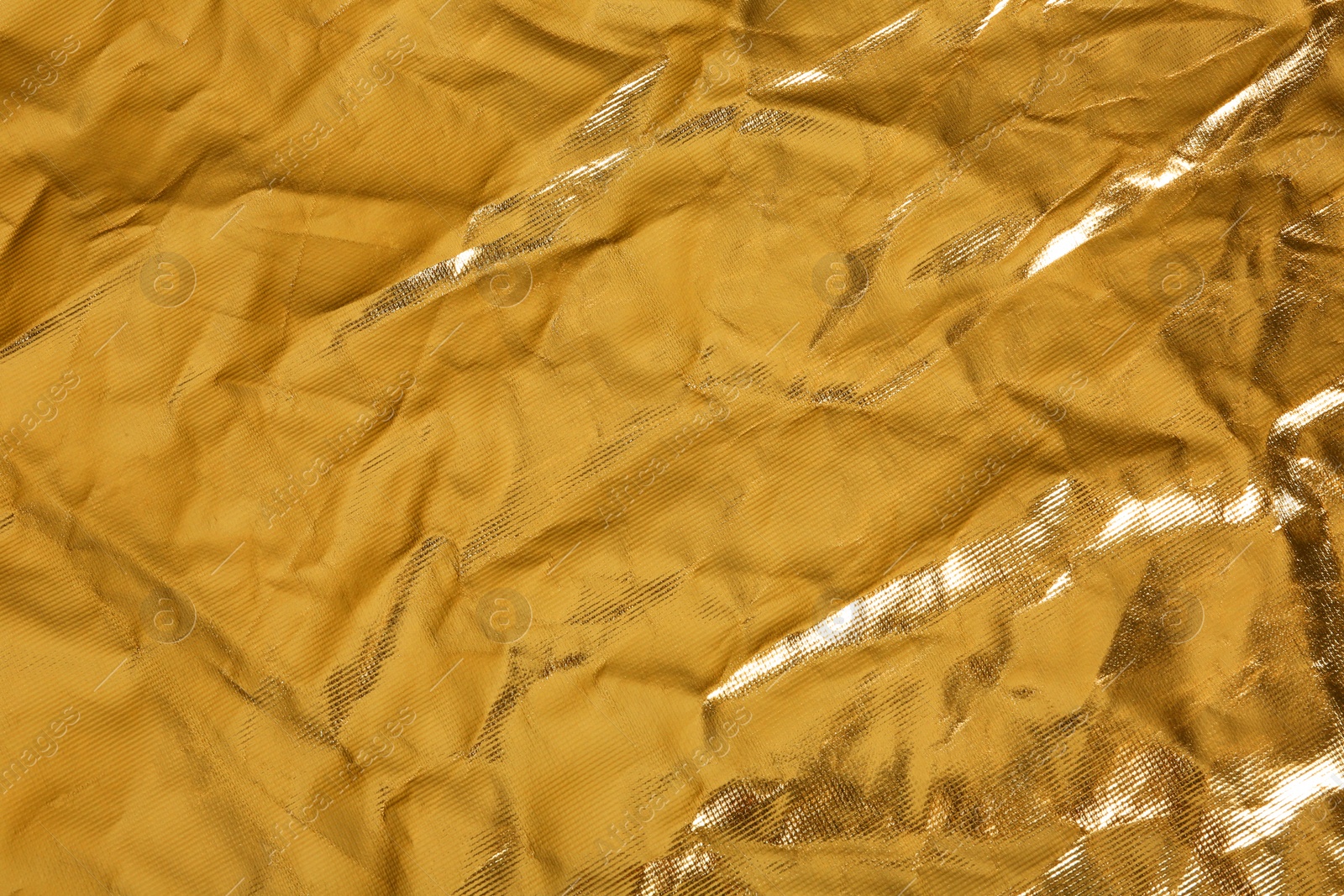 Photo of Crumpled golden foil as background, closeup view