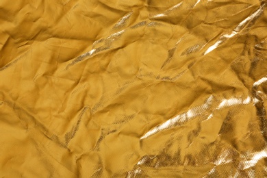 Photo of Crumpled golden foil as background, closeup view