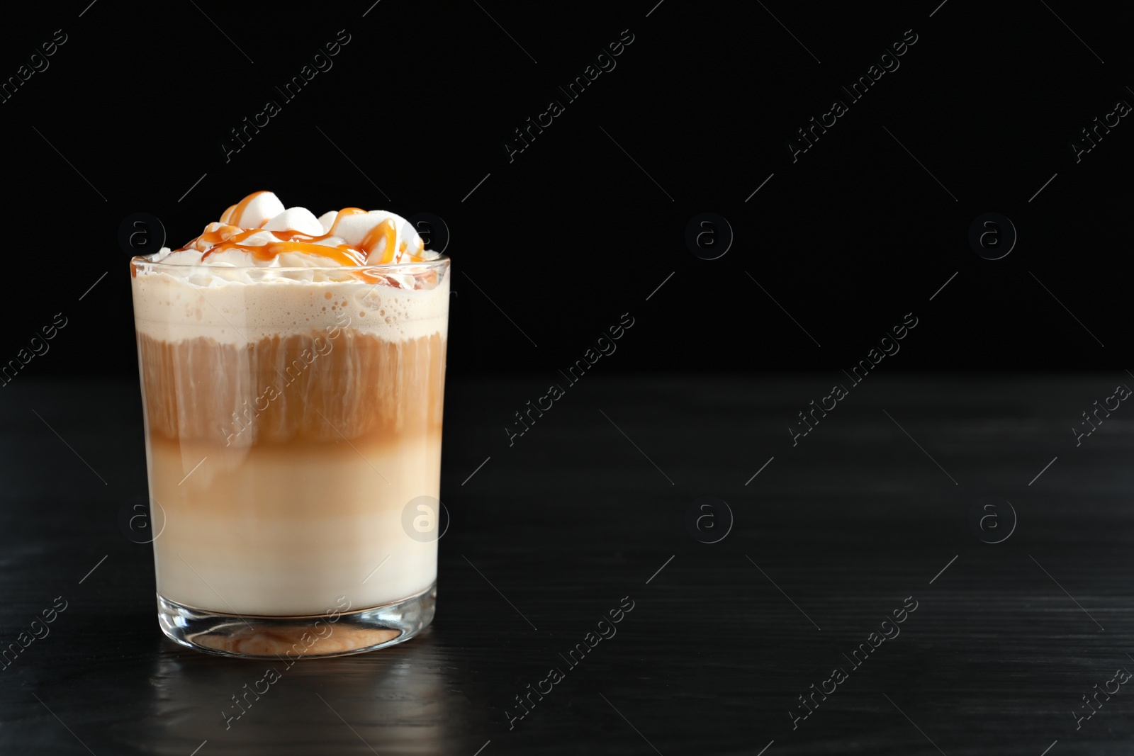 Photo of Glass with delicious caramel frappe on table