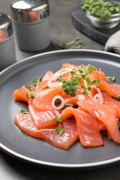 Photo of Salmon carpaccio with capers, onion and microgreens on plate, closeup