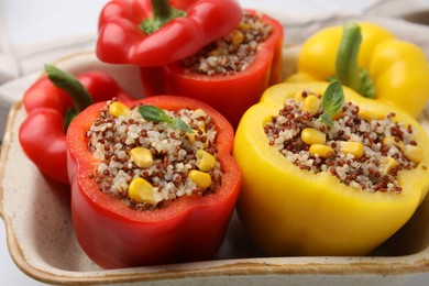 Photo of Quinoa stuffed bell peppers and basil in baking dish, closeup