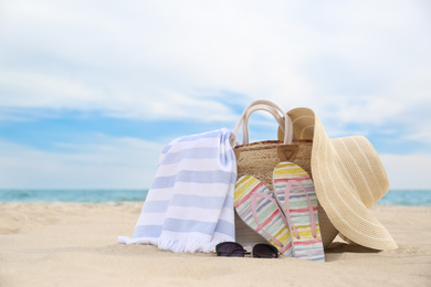 Photo of Different stylish beach objects on sand near sea
