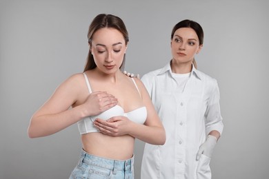 Photo of Mammologist checking woman's breast on gray background