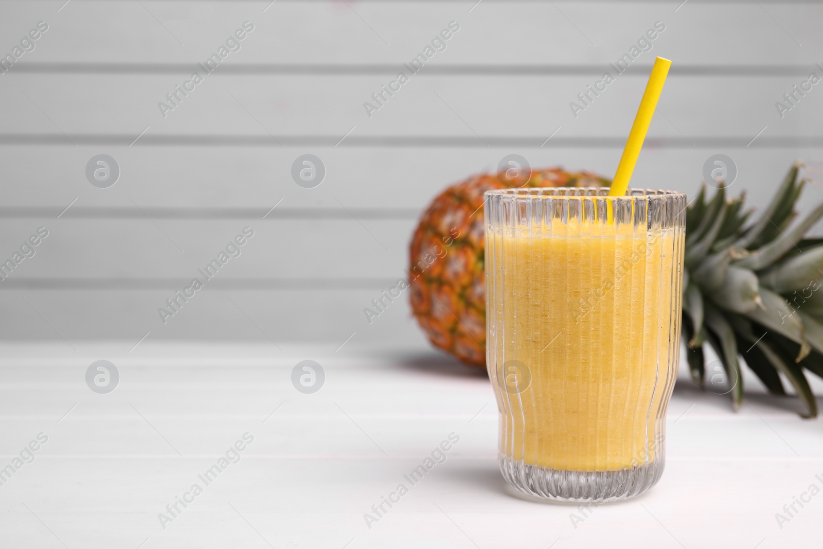 Photo of Tasty pineapple smoothie and fresh fruit on white table, space for text