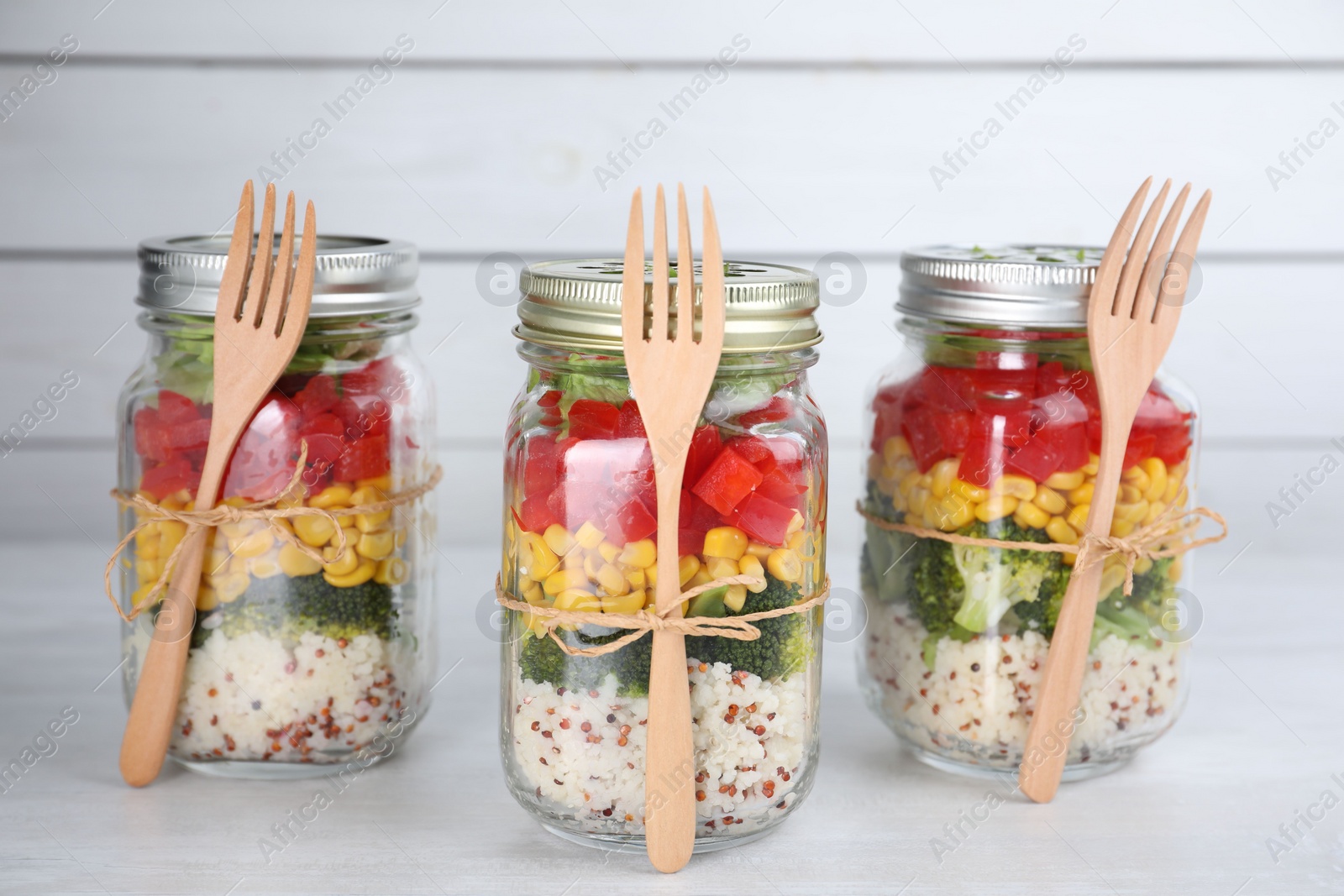 Photo of Glass jars with healthy meal on white wooden table