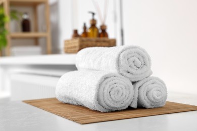 Photo of Rolled soft towels on white table in bathroom