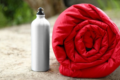 Rolled sleeping bag and bottle on sand