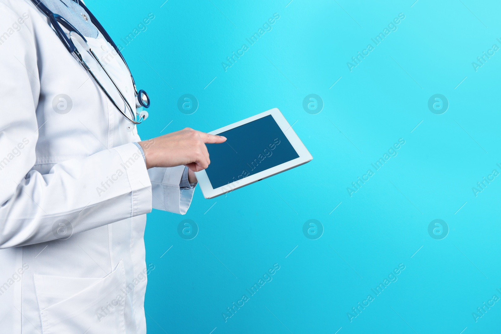 Photo of Female doctor holding modern tablet on color background, closeup with space for text