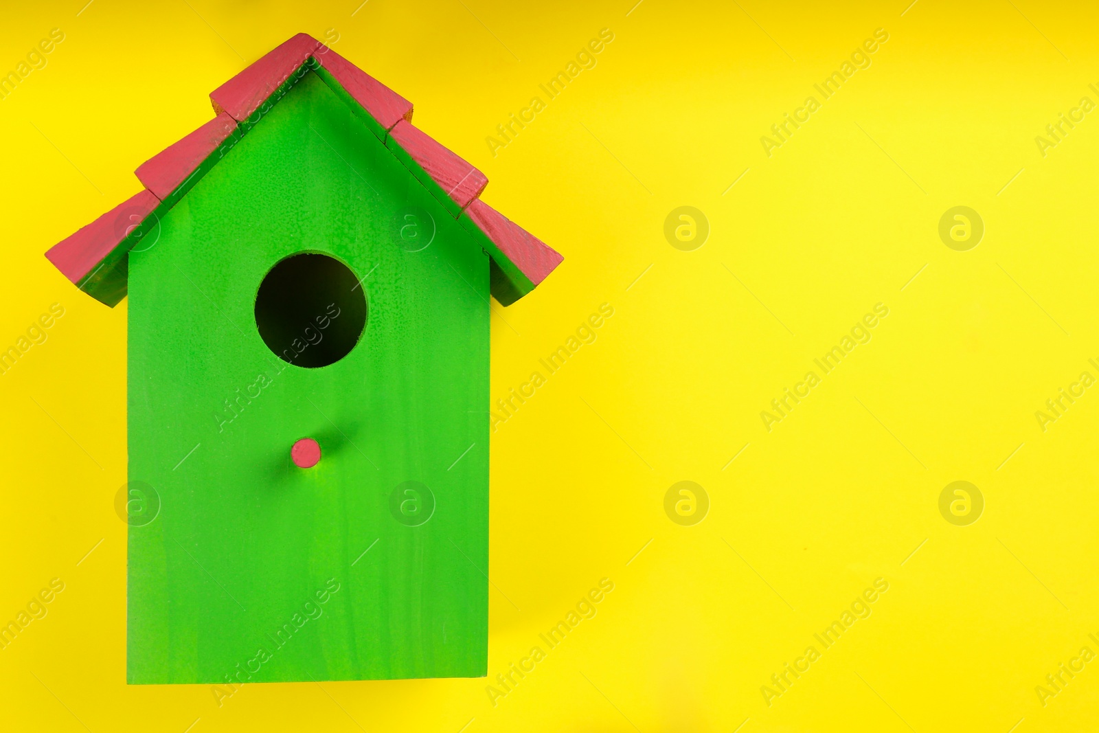 Photo of Beautiful bird house on yellow background, top view. Space for text