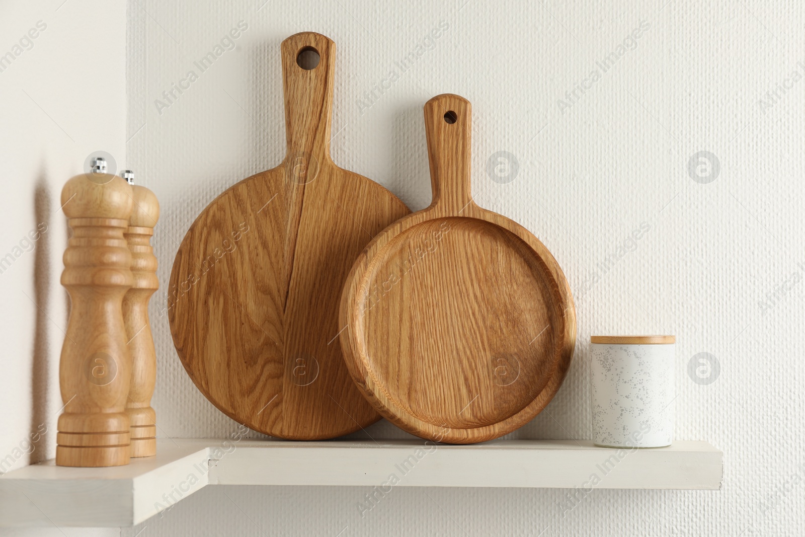 Photo of Wooden cutting boards and shakers on white shelf