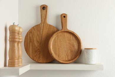 Wooden cutting boards and shakers on white shelf