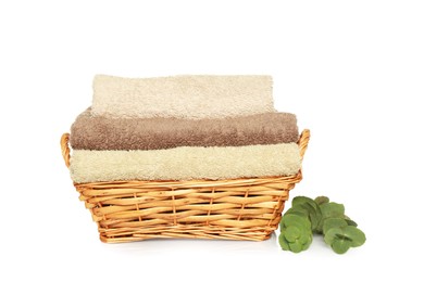 Photo of Wicker basket with folded soft terry towels and eucalyptus branch on white background