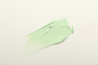 Photo of Stroke of green color correcting concealer on white background, top view