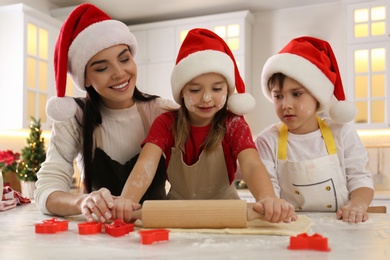 Mother and her cute little children making Christmas cookies in kitchen