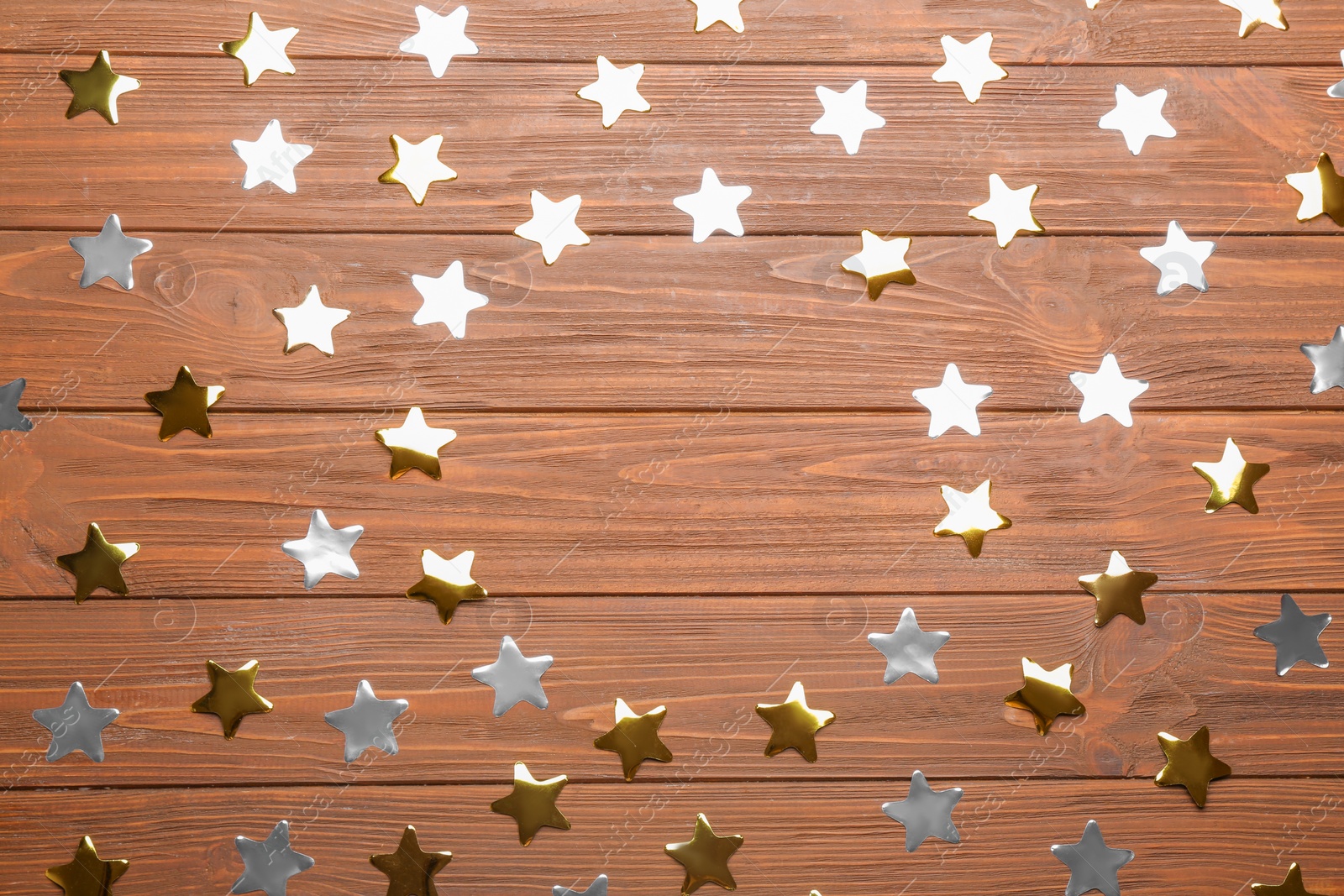 Photo of Frame made of confetti stars with space for text on wooden background, top view. Christmas celebration