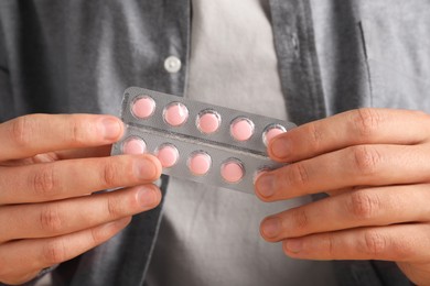 Photo of Man holding blister with pills, closeup view
