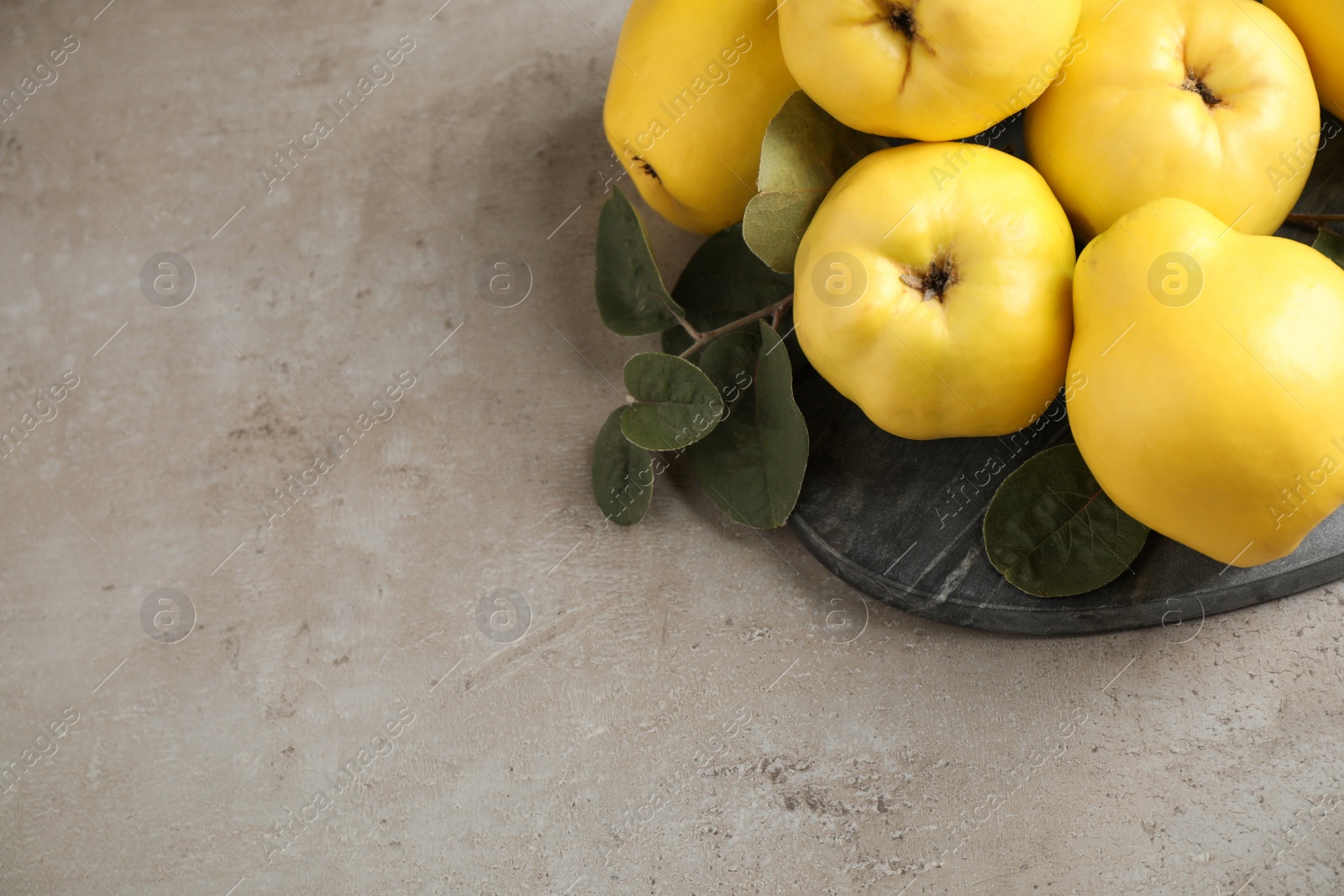 Photo of Fresh ripe organic quinces with leaves on grey table, above view. Space for text