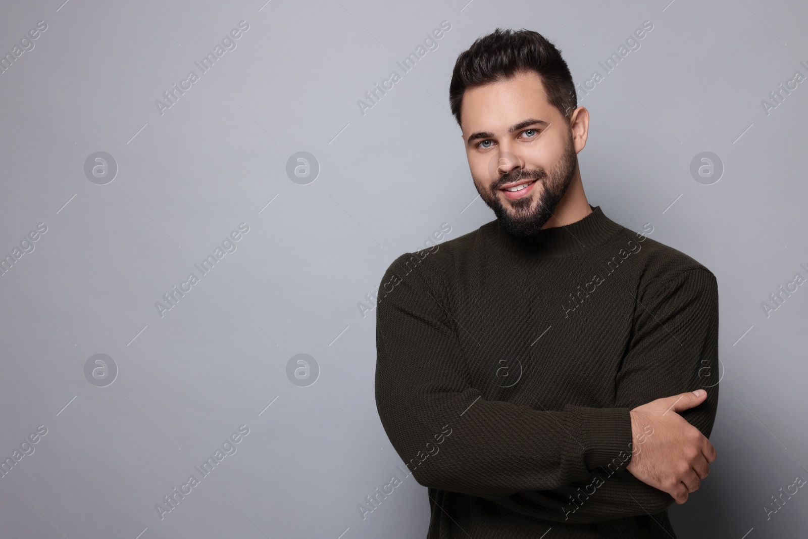 Photo of Happy man in stylish sweater on grey background, space for text